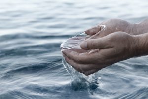 Cupped hands holding crystal-clear fresh water, symbolizing the result of Globaluf's advanced seawater reverse osmosis (SWRO) desalination technology.