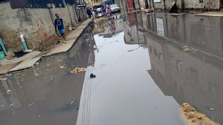 A flooded urban street with standing water and nearby buildings.