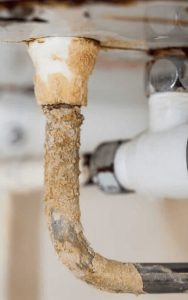 Close-up of severe limescale buildup on a water pipe caused by hard water, showing thick, crusty mineral deposits.