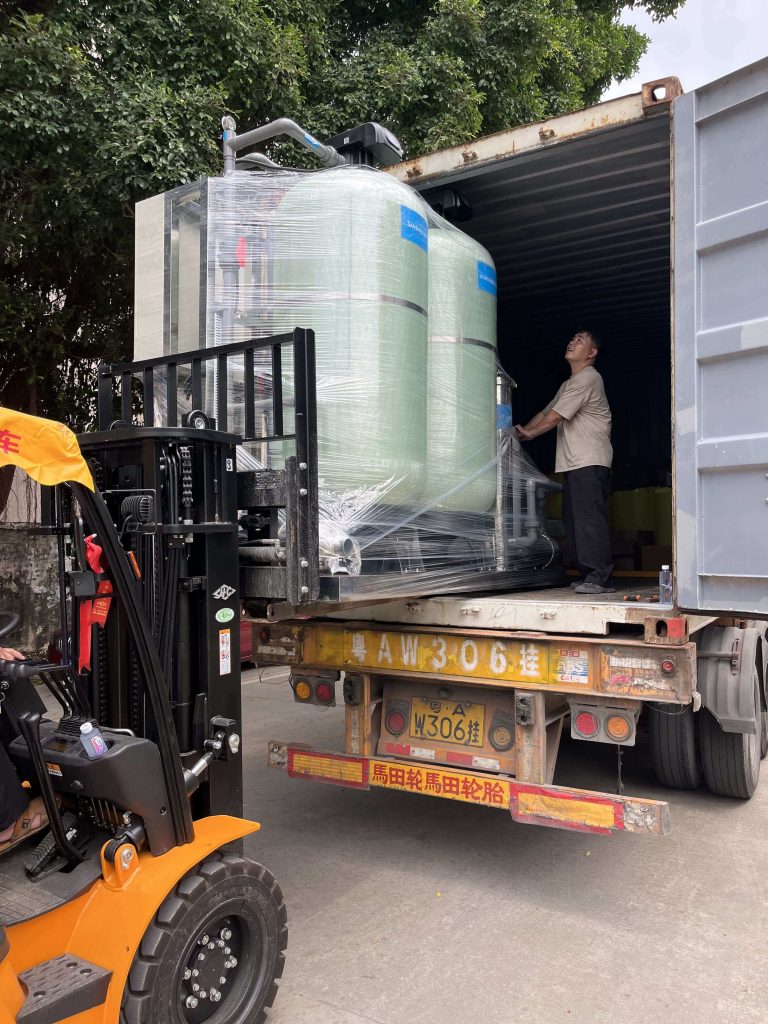 Globaluf skid-mounted ultrafiltration water treatment system wrapped in protective film being loaded into a shipping container by a forklift for export to Malaysia.
